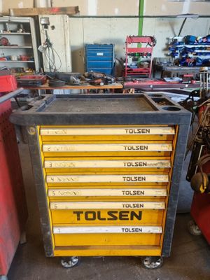 une boîte à outils jaune posée dans un garage, à côté d'autres outils