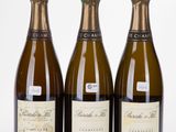 trois bouteilles de champagne posées les unes à côté des autres sur une surface blanche
