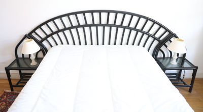 a white bed with a black headboard and two night stands