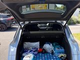 the trunk of a silver car with a lot of items in it
