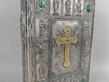 un vieux livre argenté avec une croix sur la couverture et une perle verte