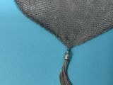 a silver mesh purse with a tassel on a blue background