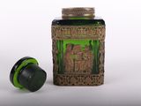 a green glass jar with a gold lid and a black lid