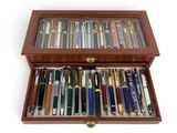 une image représentant une boîte en bois remplie de différents types de stylos