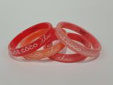 three red and orange bracelets with the names of different countries on them