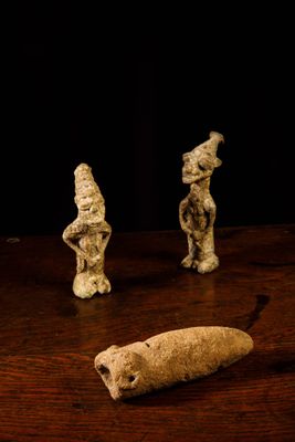 three small figurines sitting on a table next to a piece of bread