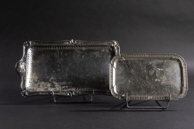 une paire de plateaux en argent posés sur un support, sur fond noir