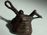 une petite statue représentant un oiseau perché sur un panier en fil de fer