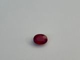 an oval shaped red stone on a white surface