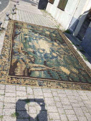 un tapis posé sur le trottoir, sur lequel se détache l'ombre d'une personne