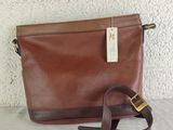 a brown leather bag with a brown strap and a tag on it