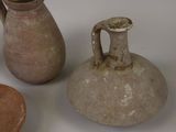 three vases and a bowl are sitting on a white surface