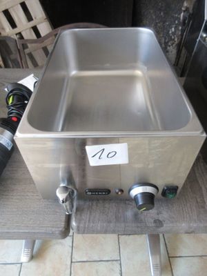 une casserole en acier inoxydable posée sur une table, à côté d'une bouteille de vin