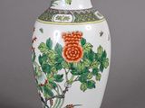 a white vase with a red flower and green leaves on it