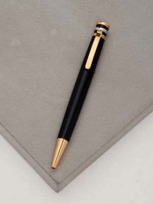 black and gold ballpoint pen laying on top of a gray surface