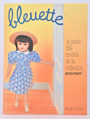 La poupée porte une robe bleue et un chapeau de paille.