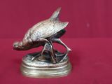 une statue en bronze représentant un oiseau perché sur un socle
