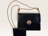 two pieces of black alligator skin purses on a white surface