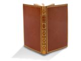un vieux livre à la couverture dorée posé sur une surface blanche