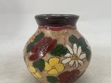 a small vase with flowers painted on it on a table
