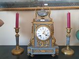 une horloge posée sur une table à côté de trois bougies