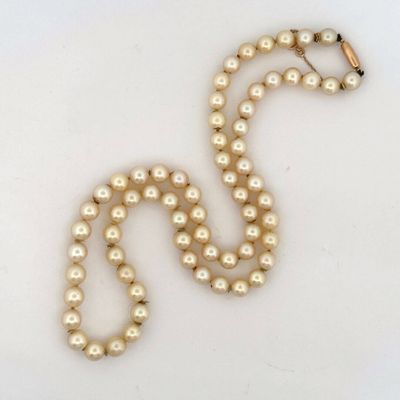 a close up of a pearl necklace on a white surface