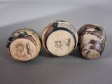 three small vases with designs on them sitting on a table