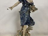 une figurine représentant une femme tenant un panier de fleurs