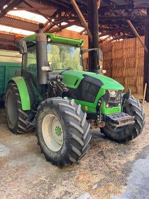 a green tractor that is parked in a barn