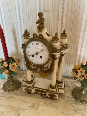 a clock that is sitting on a table next to some candles