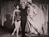 black and white photograph of a man and two women standing on a stage