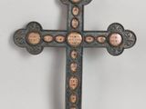 un gros plan d'une croix posée sur une surface blanche, sur laquelle figurent de nombreux visages
