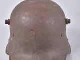un vieux casque est posé sur une surface blanche, à côté d'une paire de ciseaux