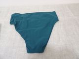 the bottom of a green bikinisuit laying on top of a bed