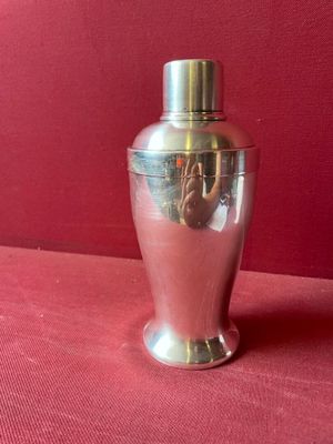 un vase argenté posé sur une surface rouge, avec un mur rouge en arrière-plan