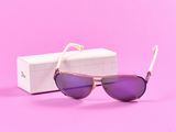 des lunettes de soleil dans une boîte posée sur une surface rose, avec un fond rose