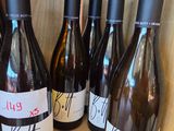 several bottles of wine are lined up on a wooden shelf