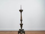 a tall metal candle holder sitting on top of a wooden floor