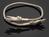un bracelet en argent orné de deux mains et d'une tête de serpent sur un fond noir