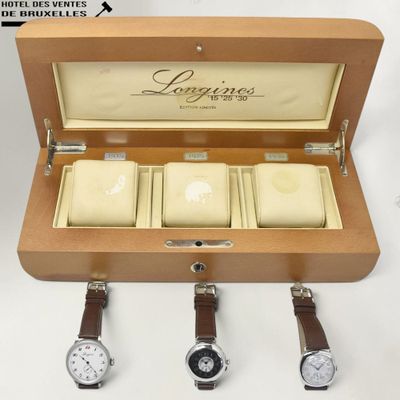 three watches in a wooden case with leather straps on a white surface