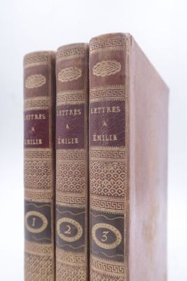 trois livres sont empilés sur une surface blanche