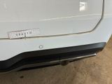the rear end of a white car with a sticker on it ' s bumper