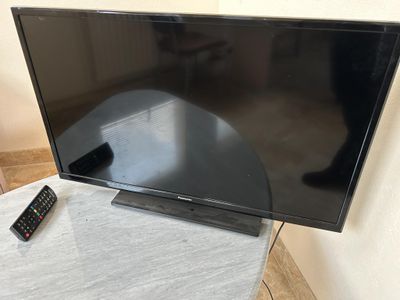un téléviseur avec sa télécommande posé sur une table devant un mur