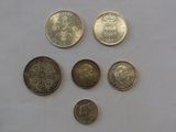 six different british coins sitting on top of a white surface