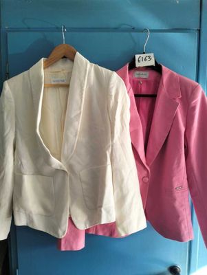 two jackets hanging on a blue wall next to each other