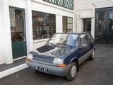 a small blue car parked in front of a building