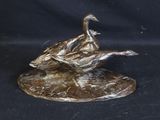 a bronze sculpture of a bird on a rock