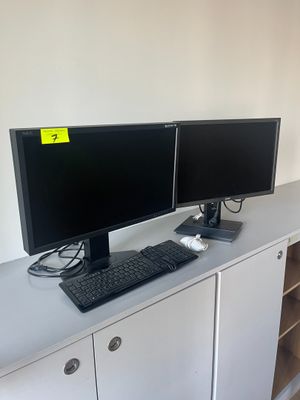 deux écrans d'ordinateur posés sur un bureau blanc