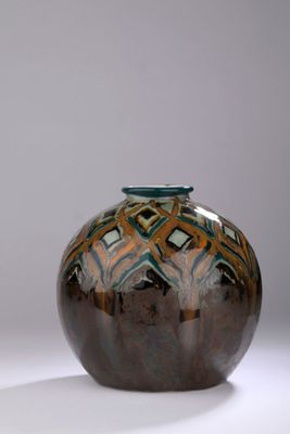 un vase brun et bleu posé sur une surface blanche