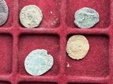 several ancient roman coins are in a red tray on a table
